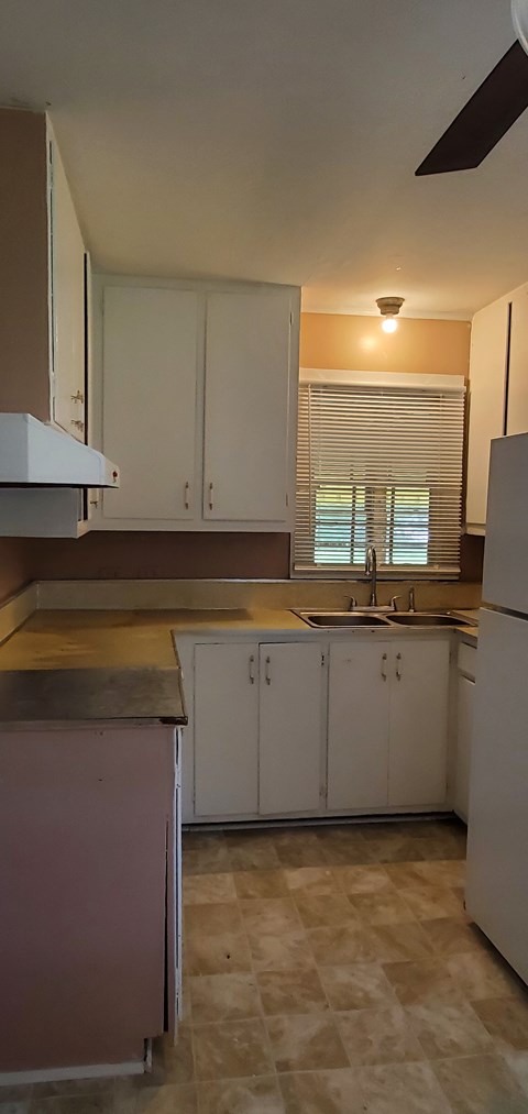 A kitchen with white cabinets and a pink counter.