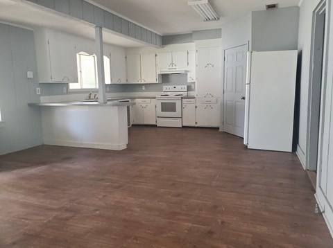 an empty kitchen with white cabinets and a wood floor