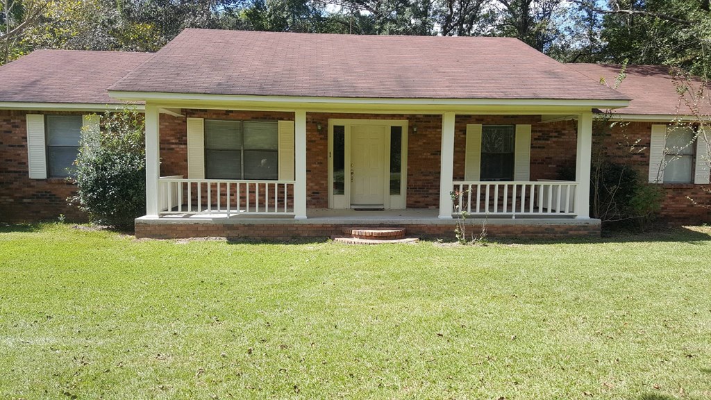 a small brick house with a porch and a lawn