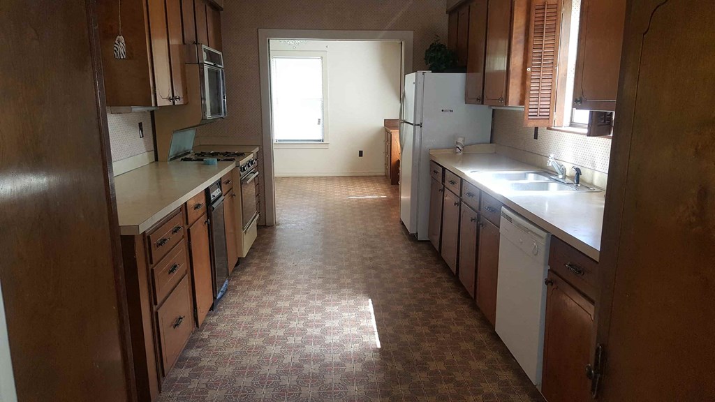 an empty kitchen with wooden cabinets and a tile floor