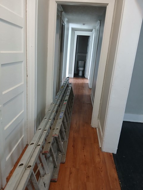 a hallway with wood flooring and a ladder on the floor