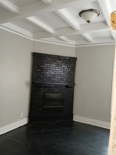 the living room has a brick fireplace and a coffered ceiling