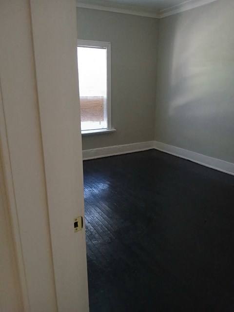 an empty room with black flooring and a window