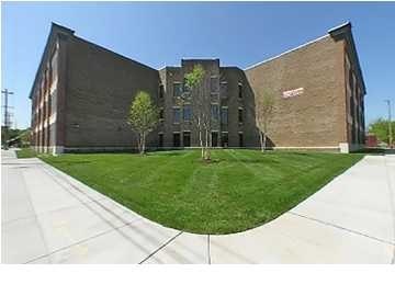 A modern building with a curved design and a green lawn in front.