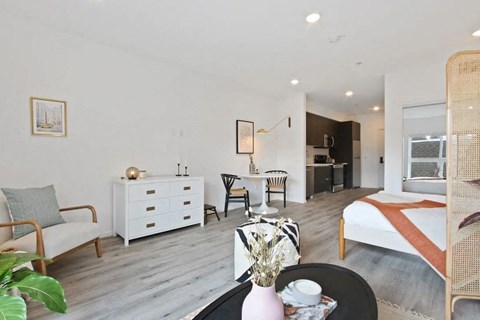 a bedroom with a bed and a living room with a desk and a kitchen