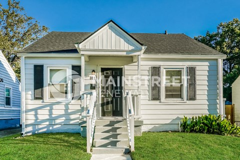 a small white house with a front porch and stairs