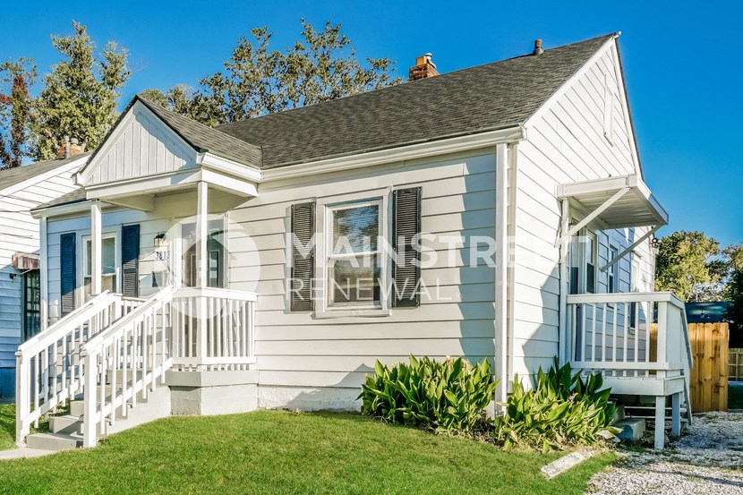 a small white house with a porch and stairs