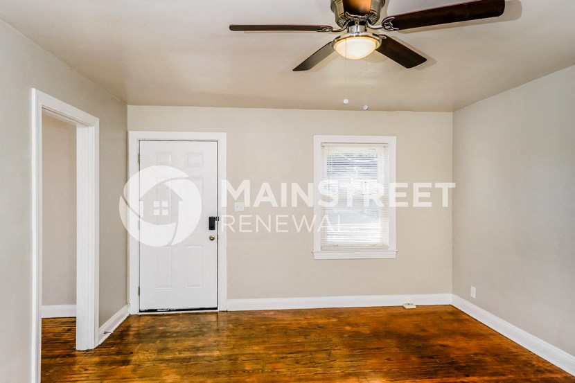 a living room with a white door and a ceiling fan