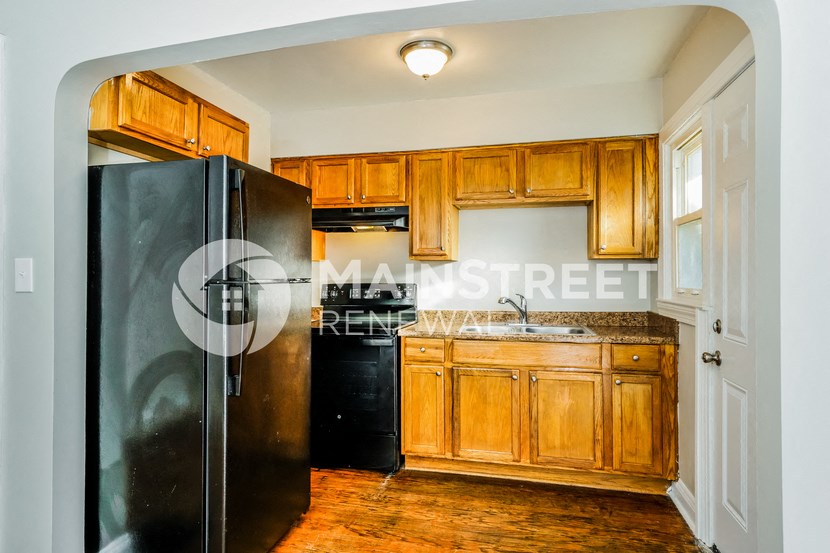 a kitchen with wooden cabinets and a black refrigerator