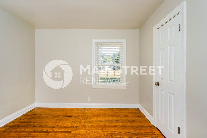 a bedroom with a hardwood floor and a white door