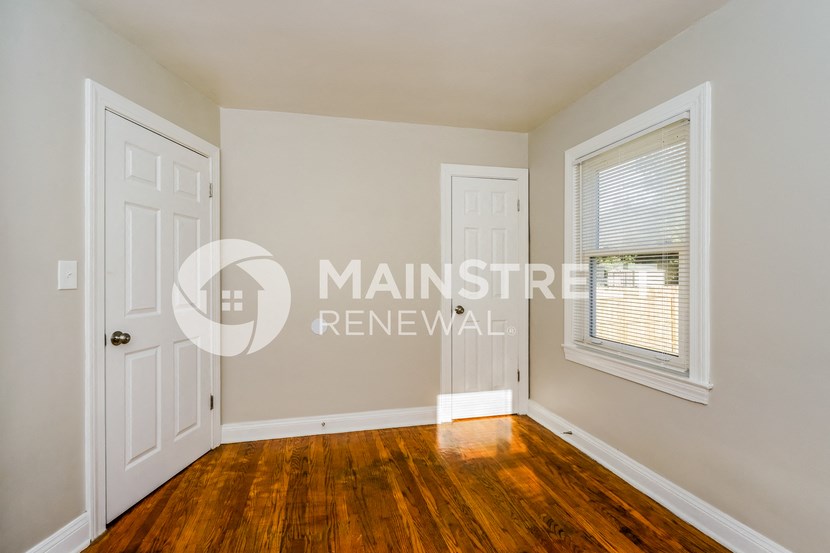 a bedroom with hardwood floors and a white door