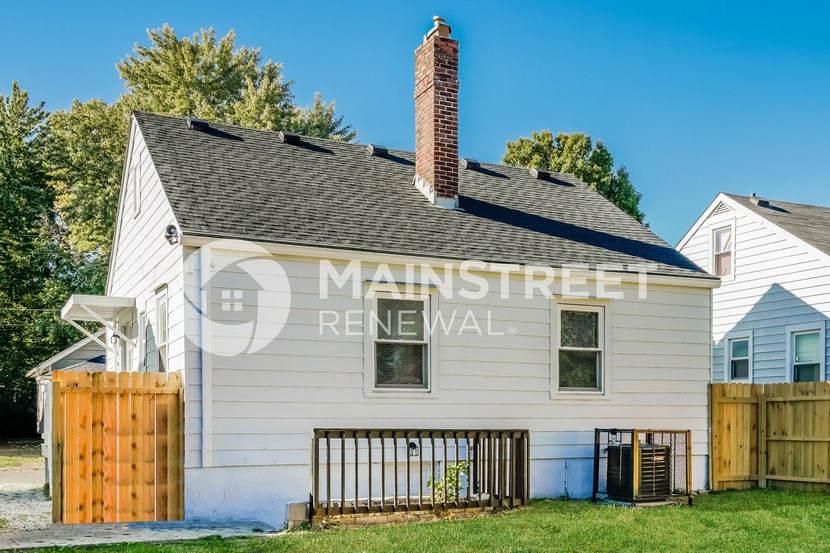 a small white house with a fence and a roof