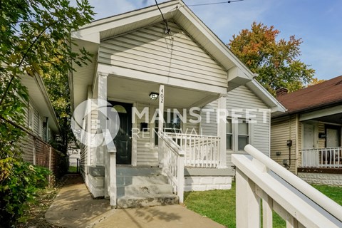 a small white house with a porch and a staircase