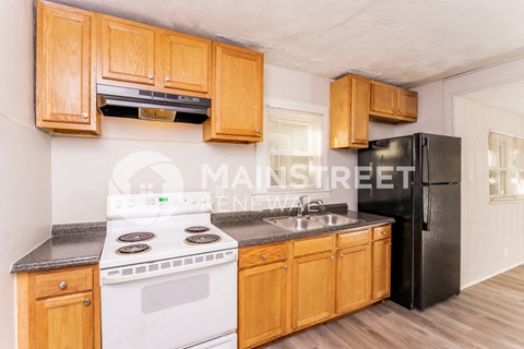 a kitchen with wood cabinets and white appliances and a black refrigerator