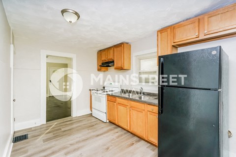 a kitchen with wooden cabinets and a black refrigerator