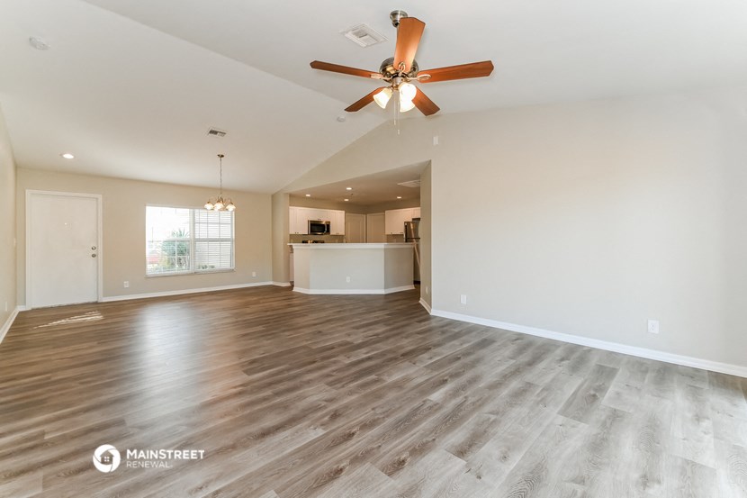 the living room and kitchen of an empty house with a ceiling fan