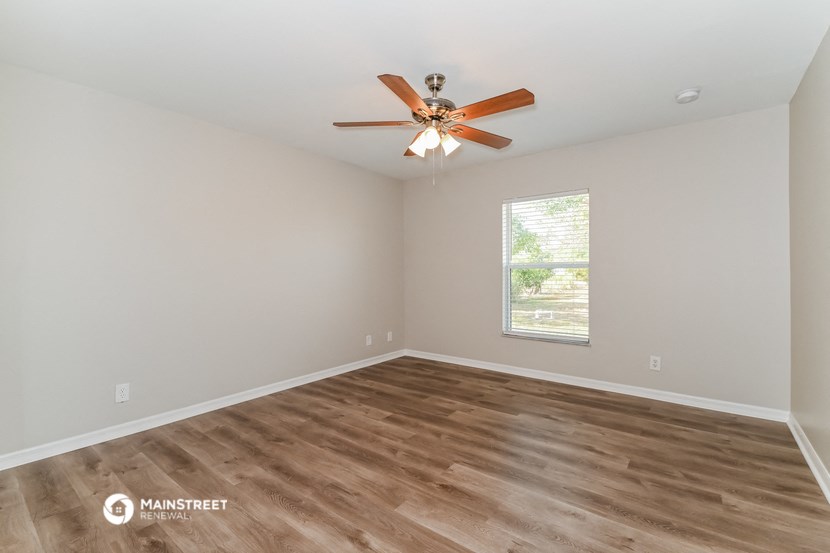the spacious living room with wood flooring and a ceiling fan