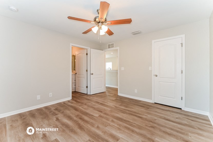the living room is spacious and has a ceiling fan