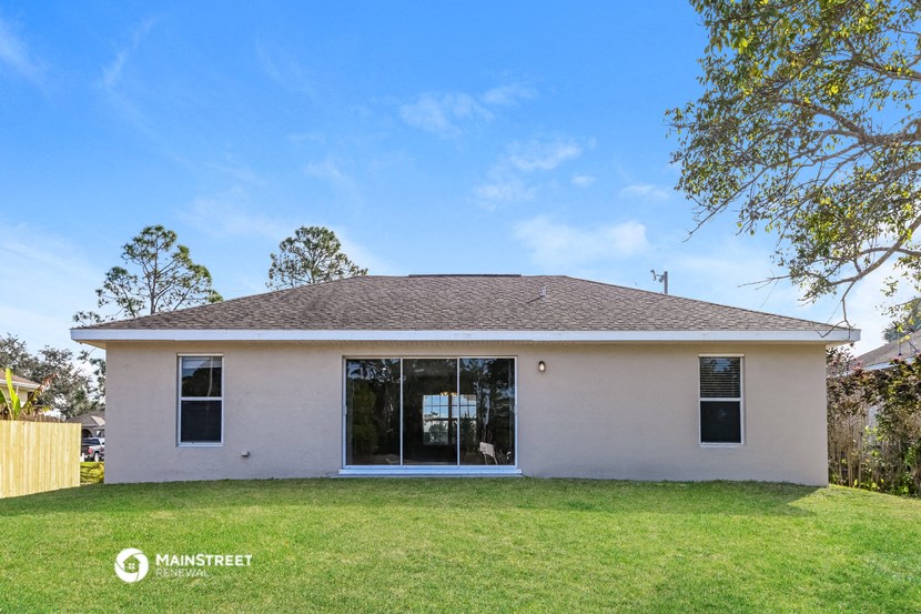 a small white house with a lawn and a tree