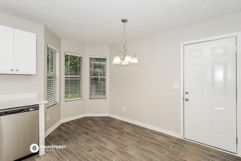 an empty kitchen and dining room with a white door