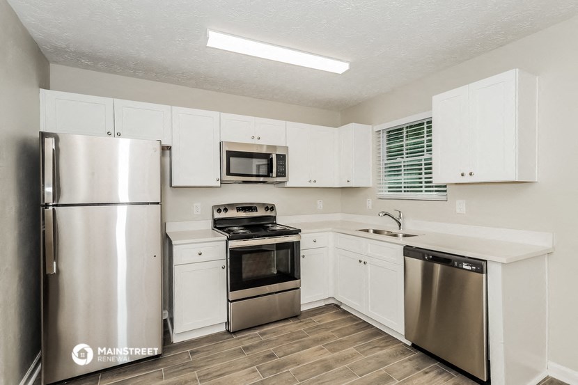 a white kitchen with stainless steel appliances and white cabinets