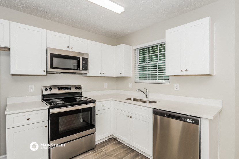 a white kitchen with stainless steel appliances and white cabinets
