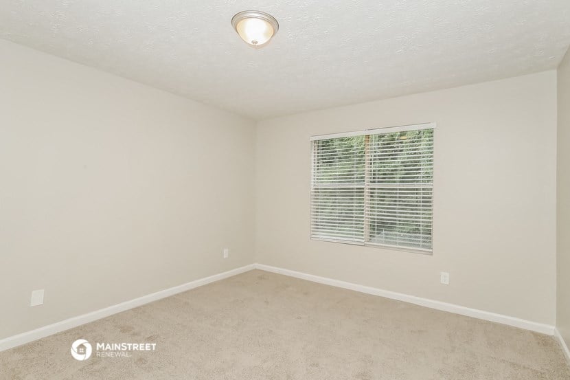 the spacious living room of a manufactured home with carpet and a window