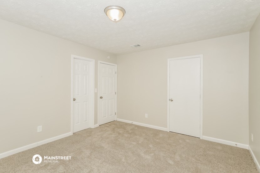 the spacious living room with two doors to the closet