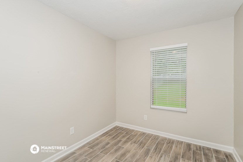 a bedroom with a window and wooden flooring and a window