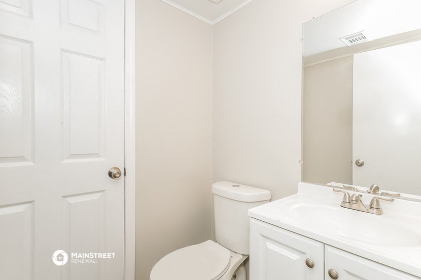 a white bathroom with a toilet sink and mirror