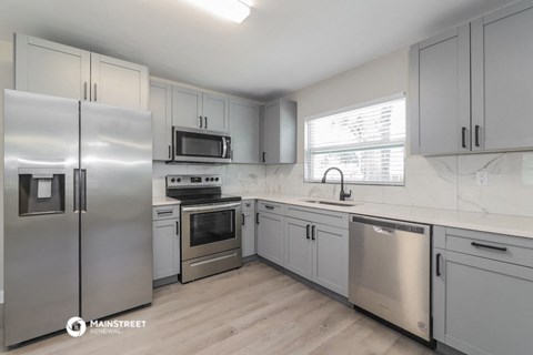 a white kitchen with stainless steel appliances and white cabinets