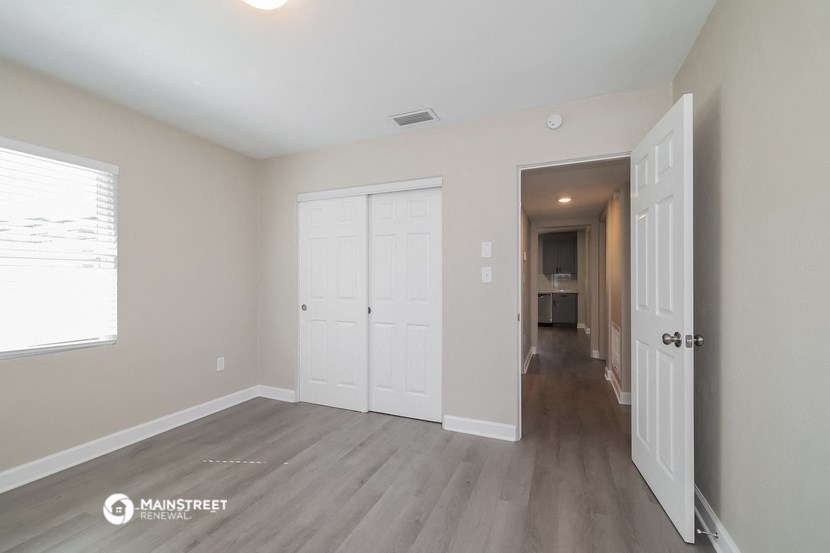 the living room and hallway of a renovated house with wooden floors and white doors