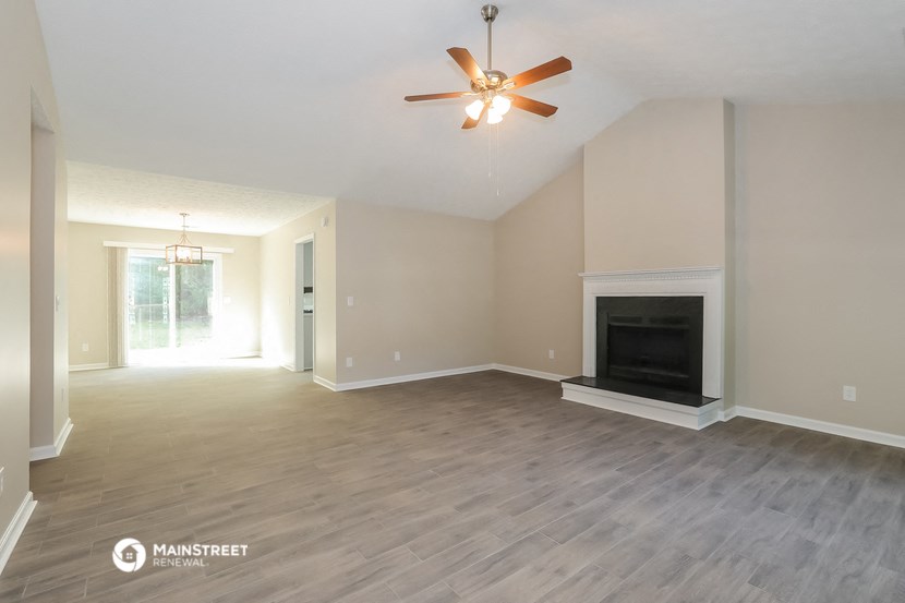 a living room with a fireplace and a ceiling fan