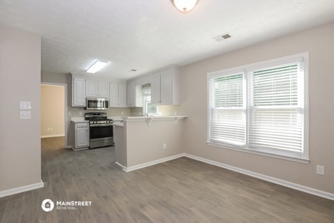 the spacious kitchen with white cabinets and a large window