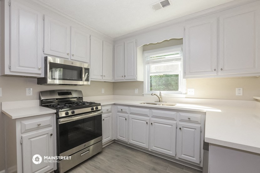a white kitchen with stainless steel appliances and white cabinets