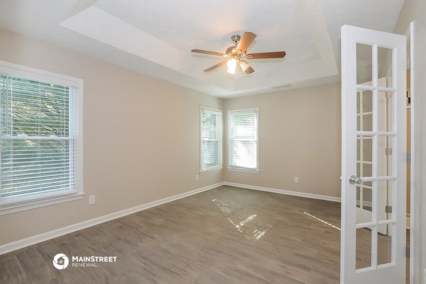 an empty living room with a ceiling fan and a window