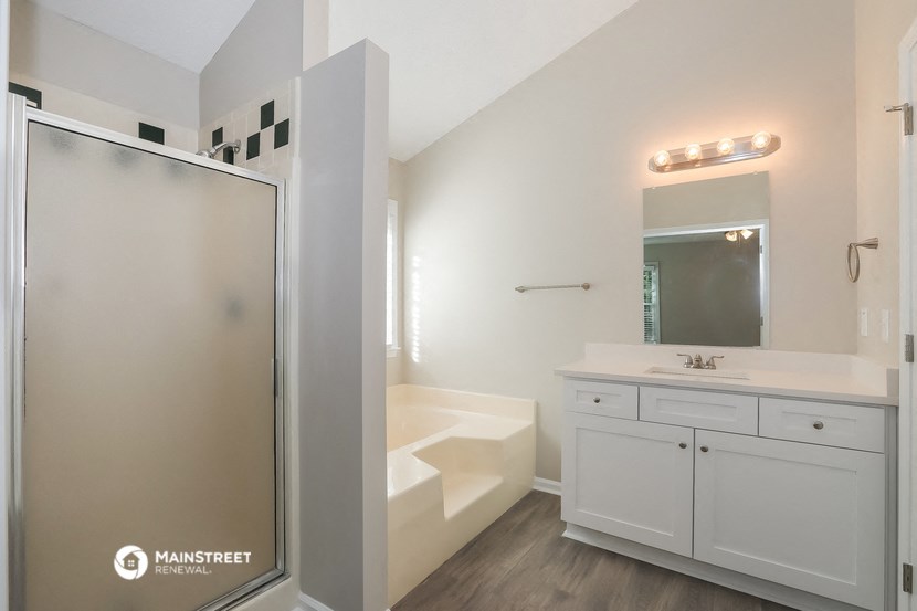 a bathroom with white cabinets and a shower and a sink