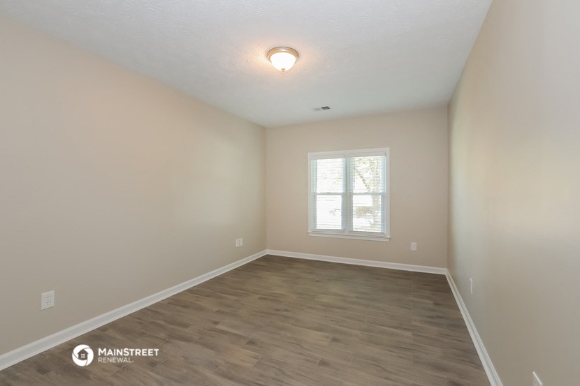 the spacious living room with hardwood flooring and a window