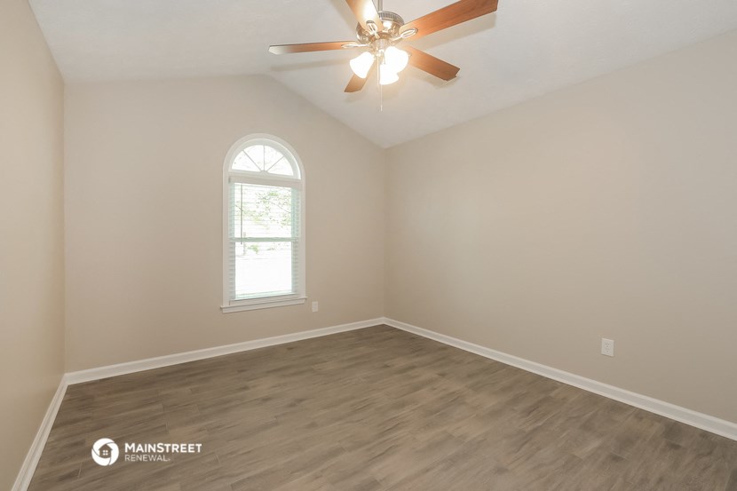 the spacious living room with hardwood floors and a ceiling fan