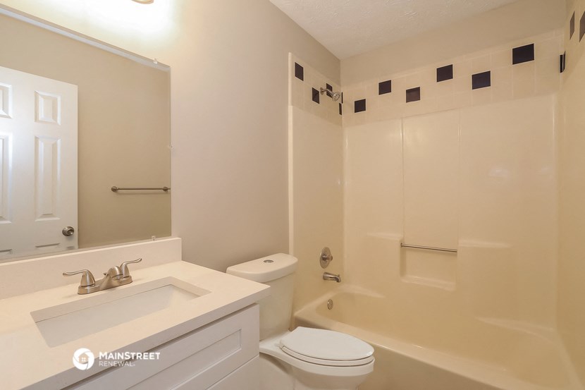 a bathroom with a toilet sink and tub and a mirror