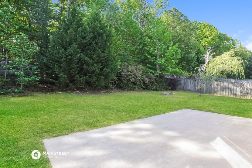 a backyard with a concrete patio and green grass and trees