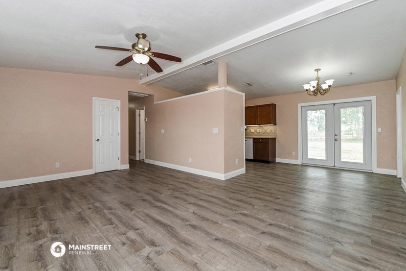 the living room of an empty house with a ceiling fan