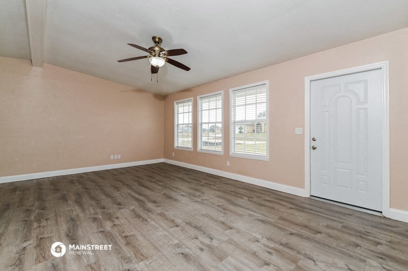 the living room of an empty home with a ceiling fan