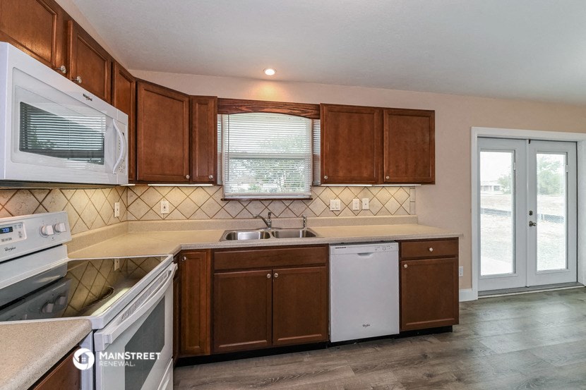 a kitchen with wooden cabinets and a white dishwasher and a sink