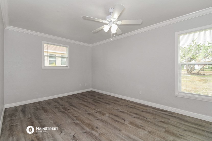the living room of a home with wood flooring and a ceiling fan