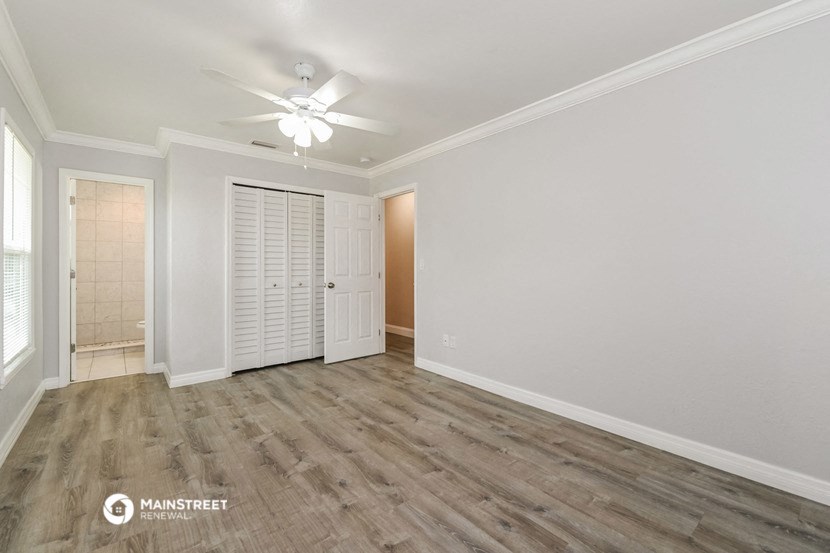 the living room of an empty home with white walls and a ceiling fan