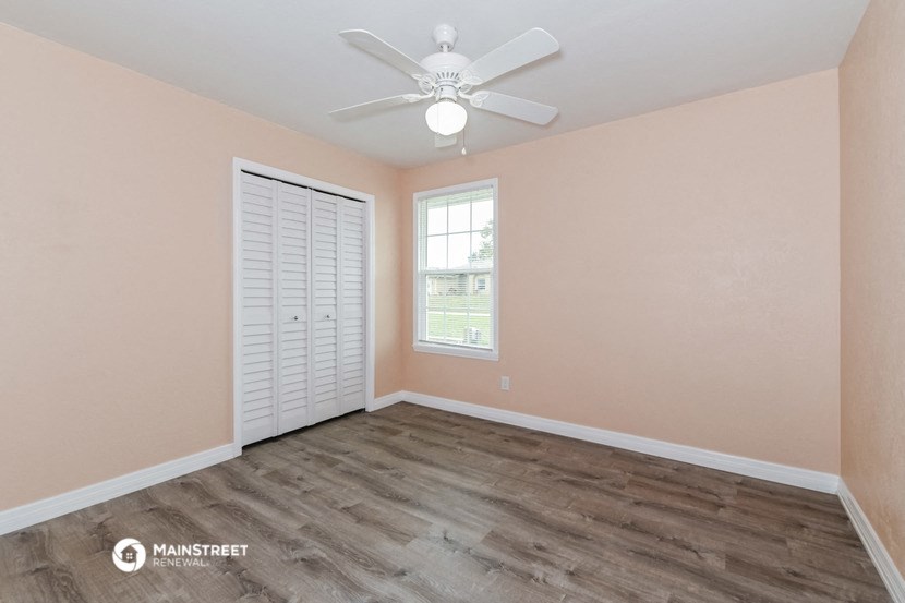 the spacious living room with wood flooring and a ceiling fan