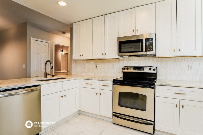 a white kitchen with stainless steel appliances and white cabinets