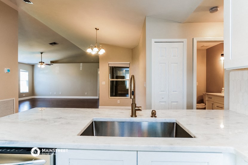 an empty kitchen with a sink and a door to the living room