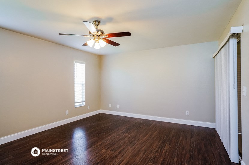the living room of an empty home with a ceiling fan